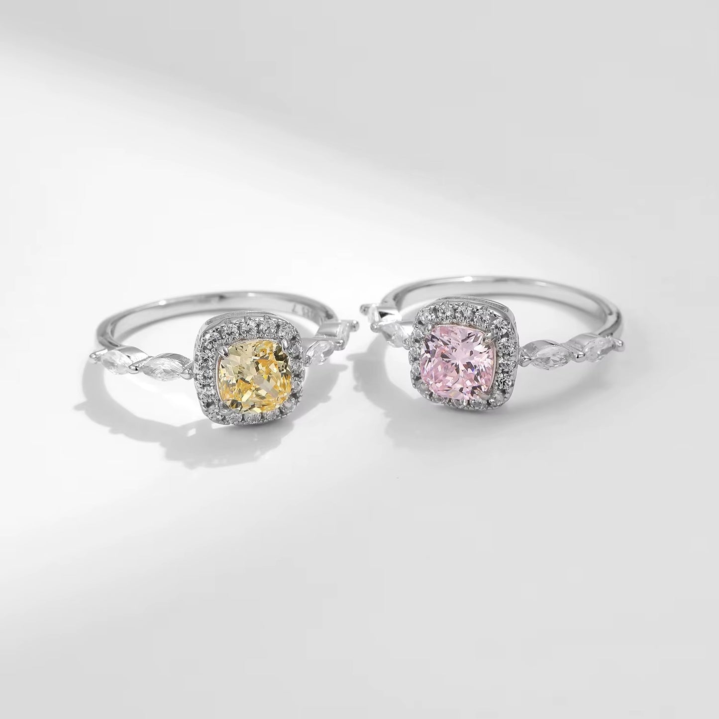Two zircon rings with yellow and pink gemstones on a light gray background