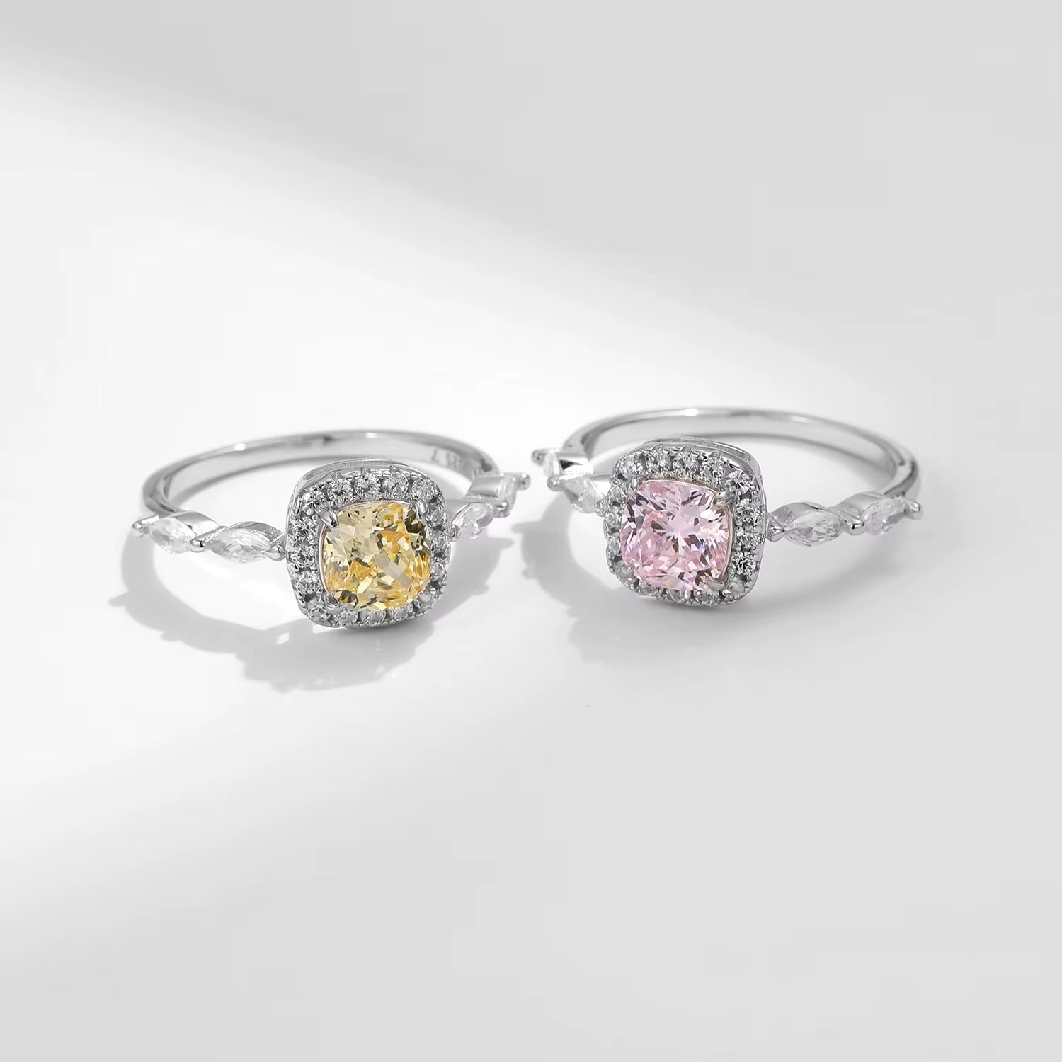 Two zircon rings with yellow and pink gemstones on a light gray background