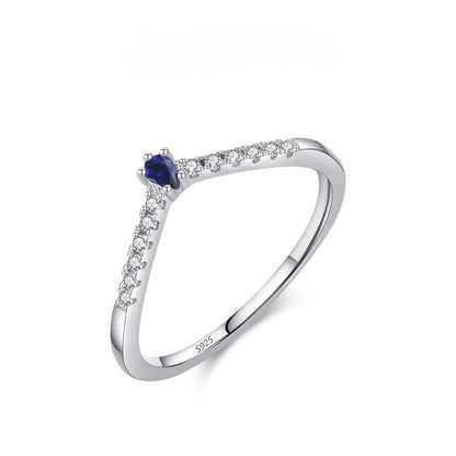 Silver ring with a blue gemstone and small zircons on a white background