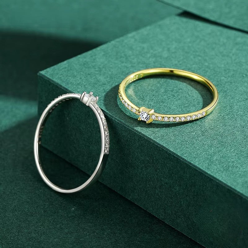 Gold and silver zircon rings on a green surface