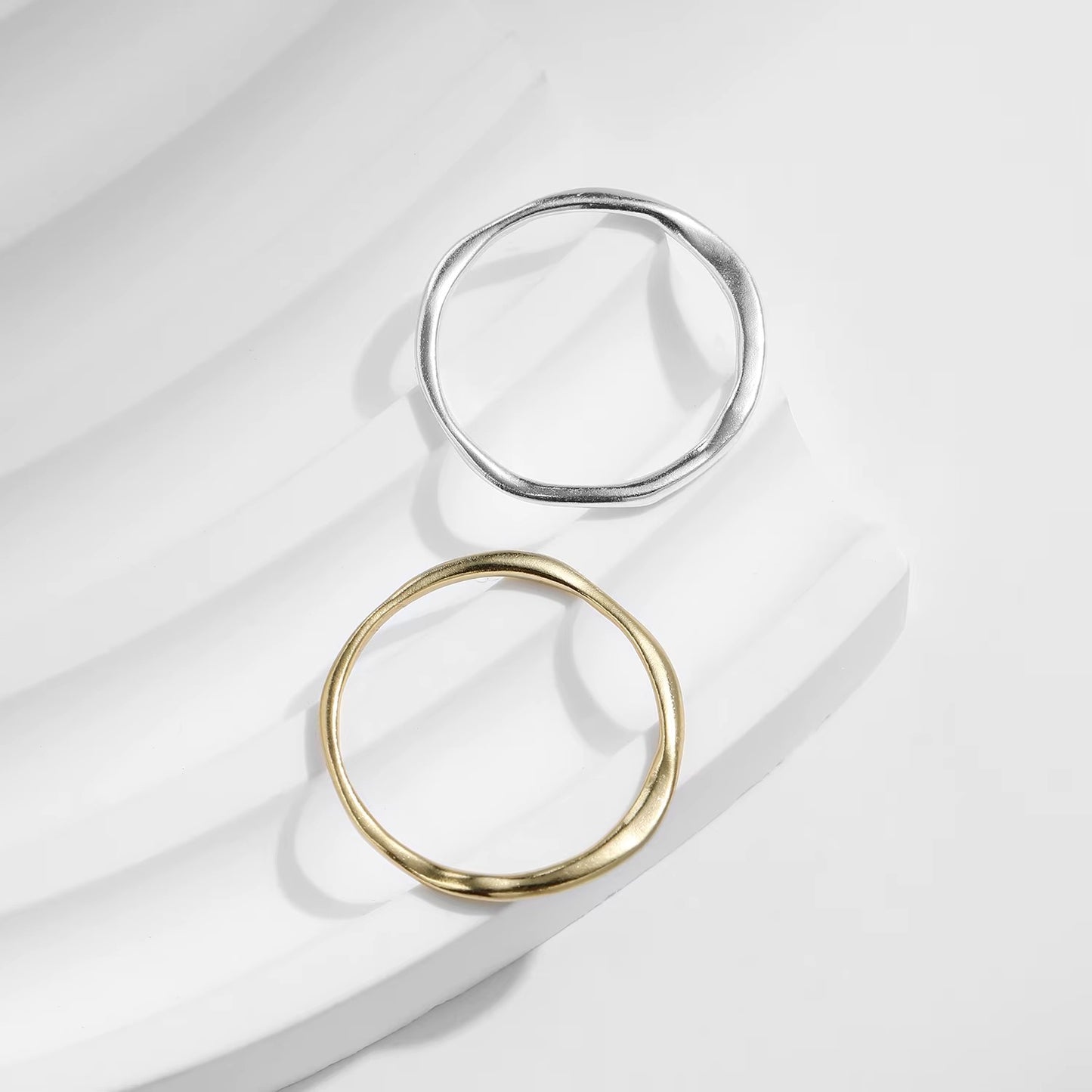 Two rings, one gold and one silver, on a light fabric background