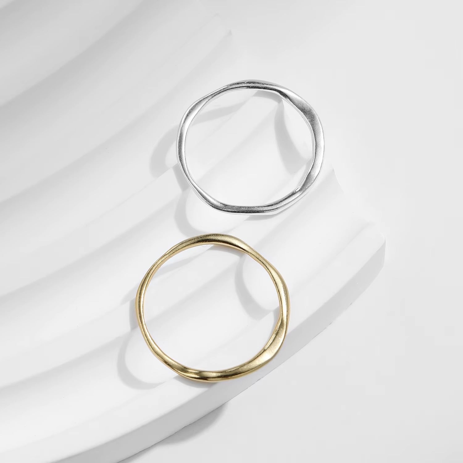 Two rings, one gold and one silver, on a light fabric background