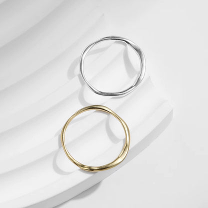 Two rings, one gold and one silver, on a light fabric background
