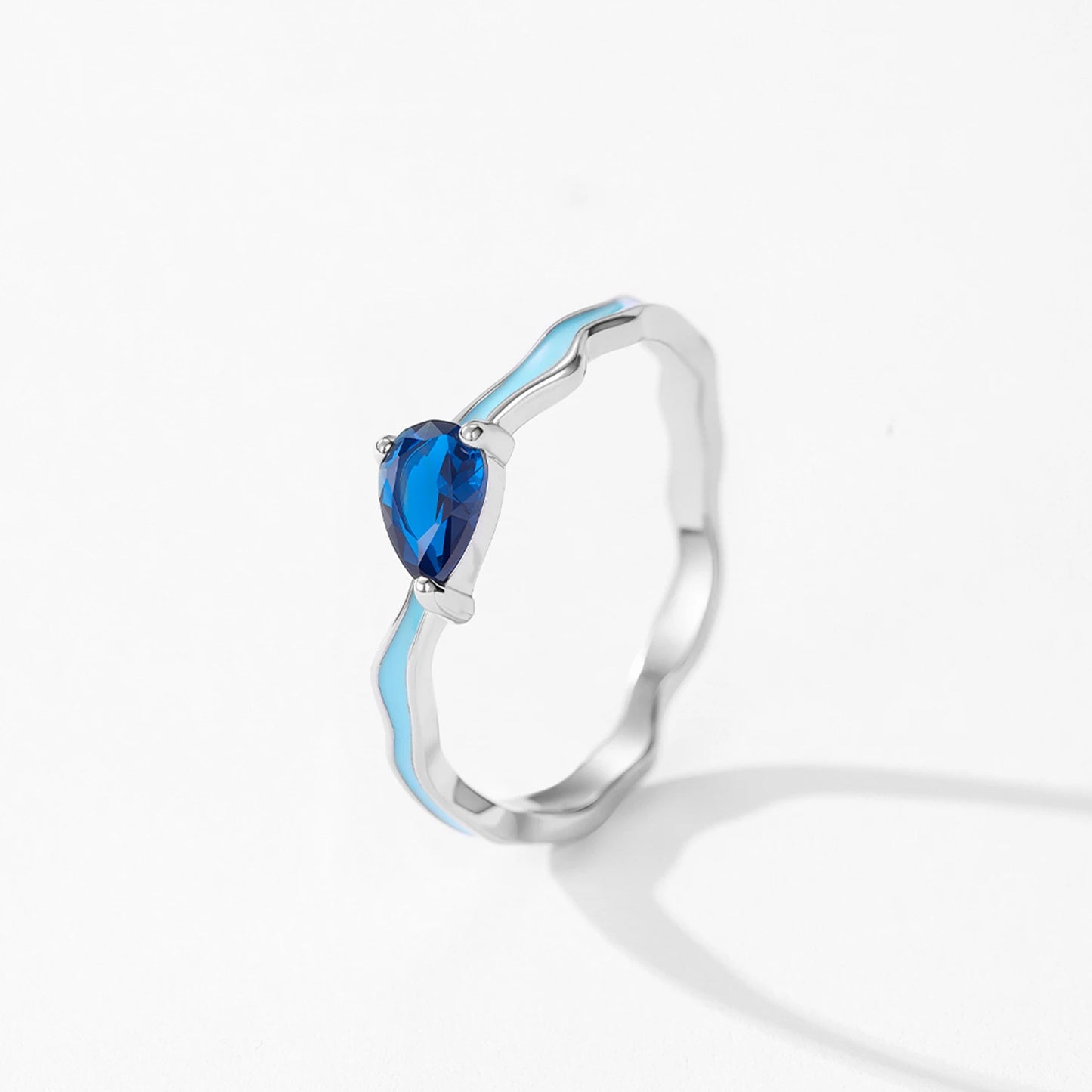 Silver ring with a heart-shaped blue gemstone on a white background