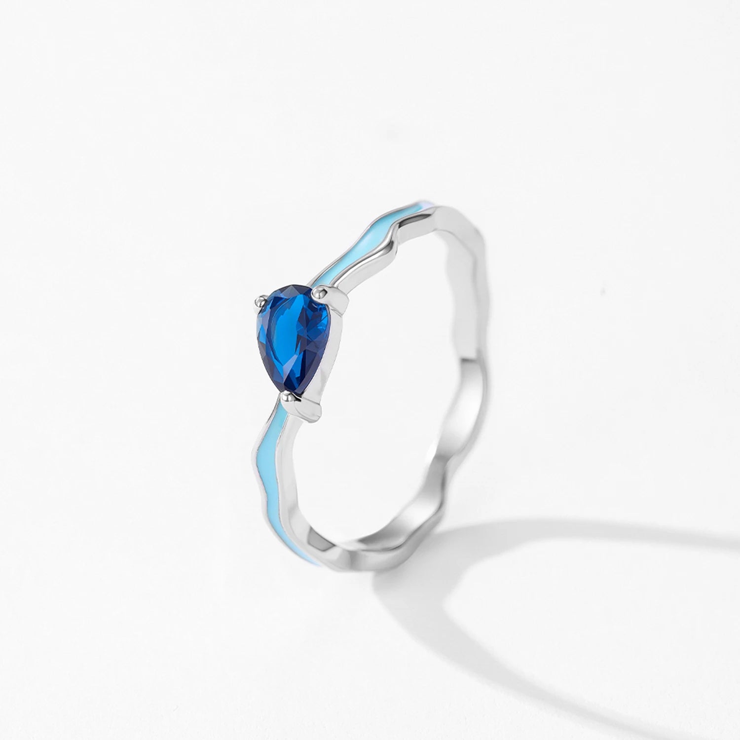 Silver ring with a heart-shaped blue gemstone on a white background
