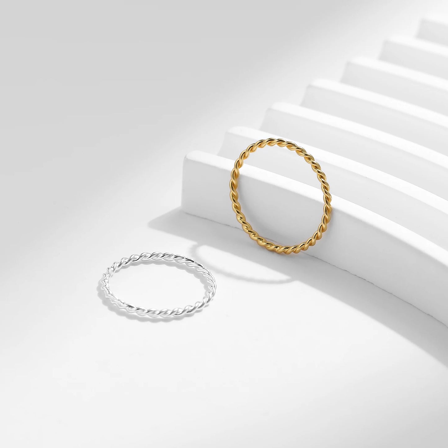 Gold and silver rings on a white surface with a light gray background