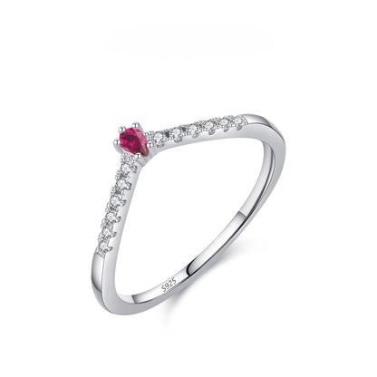 Silver ring with a red gemstone and small zircons on a white background