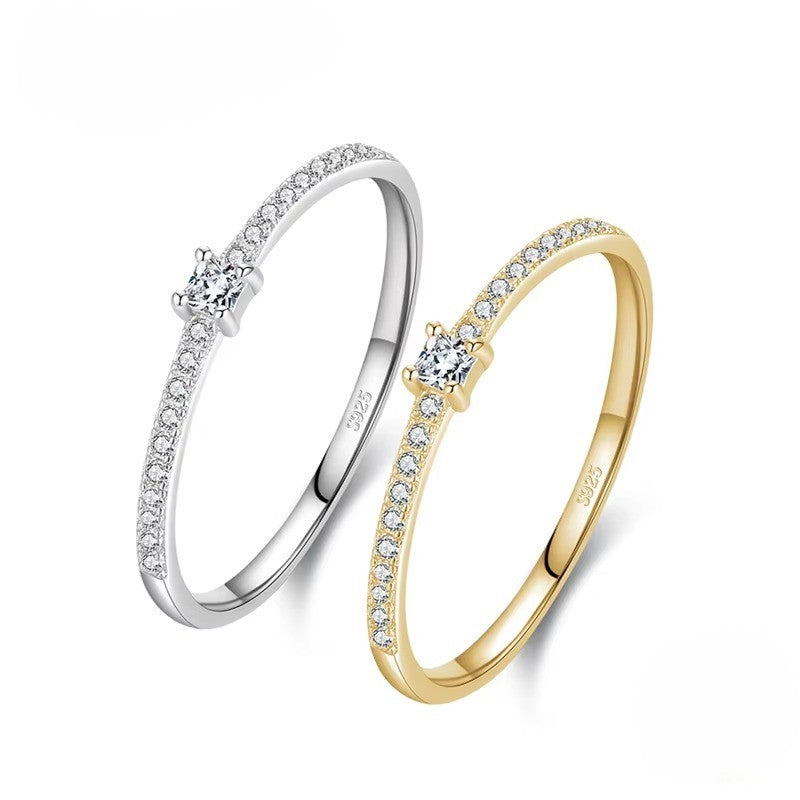 Two zircon-studded rings, one silver and one gold, on a white background.