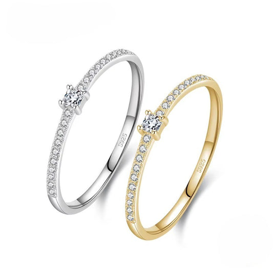 Two zircon-studded rings, one silver and one gold, on a white background.