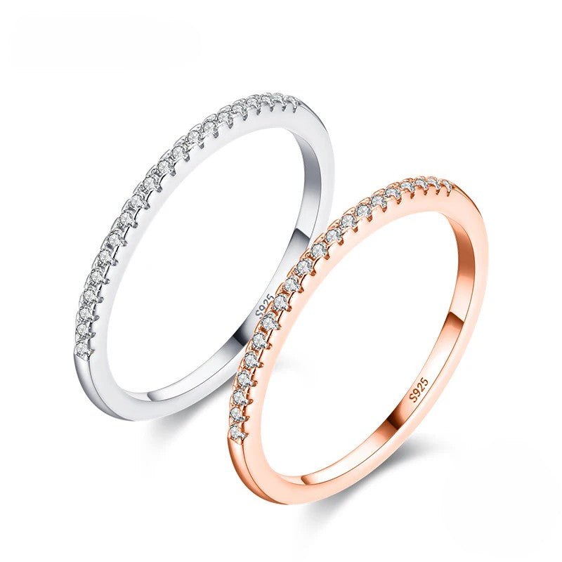 Two zircon-studded rings, one silver and one rose gold, on a white background.